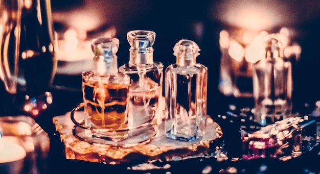Elegant glass perfume bottles, one amber, on a decorative coaster with warm, soft lighting and bokeh effects.